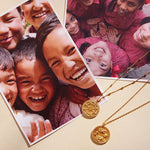 Gold-toned circular pendant necklaces with detailed engravings on fine chains displayed next to family photographs.