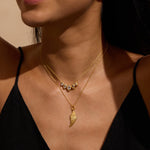 Gold-tone layered necklace with angel wing pendant and decorative beaded chain worn on model's neck.