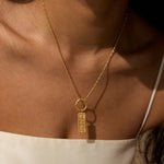 Gold-tone necklace with rectangular pendant featuring "444" numerals, worn on person.