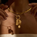 Gold beaded necklace with pendant charms including rectangular plaque with "888" detail, wing motif, and crystal stone.