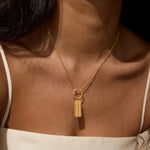 Gold-toned rectangular pendant with "111" engraved on face, hanging from delicate chain worn as necklace.