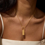 Gold-toned rectangular pendant with "111" engraved on face, hanging from delicate chain worn as necklace.