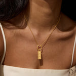 Gold-toned rectangular pendant engraved with three 8s, suspended from a delicate chain worn on the chest.