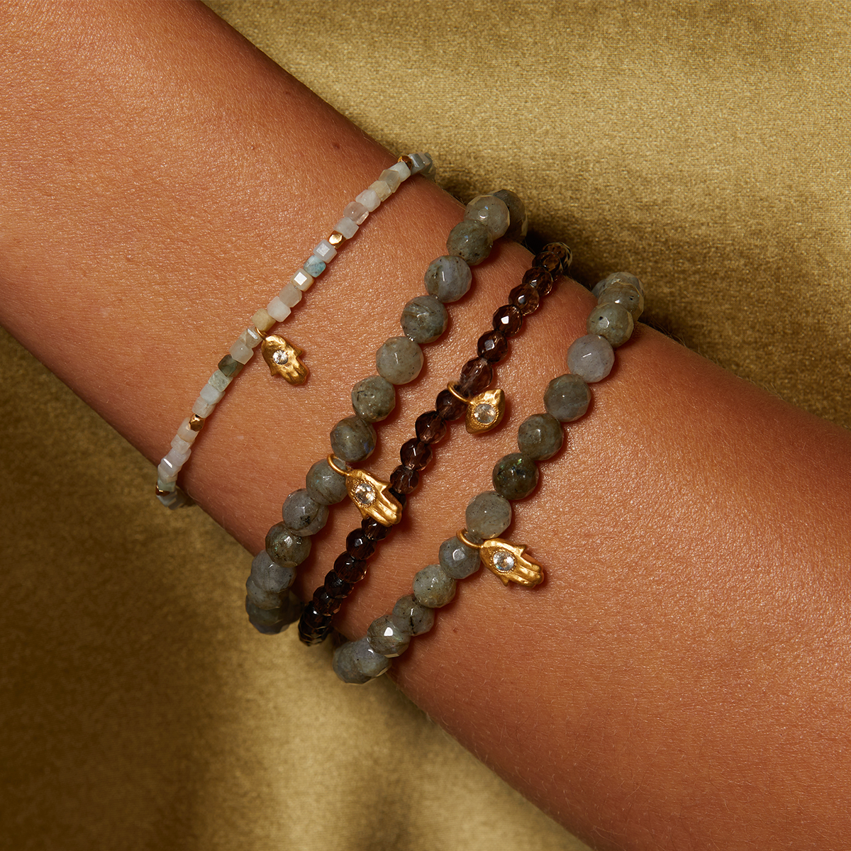 Stack of four beaded bracelets with smokey quartz, garnet, and pale stone beads featuring gold-tone metal accents.