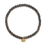 Smokey quartz beaded bracelet with gold-toned compass charm pendant featuring a blue stone center.