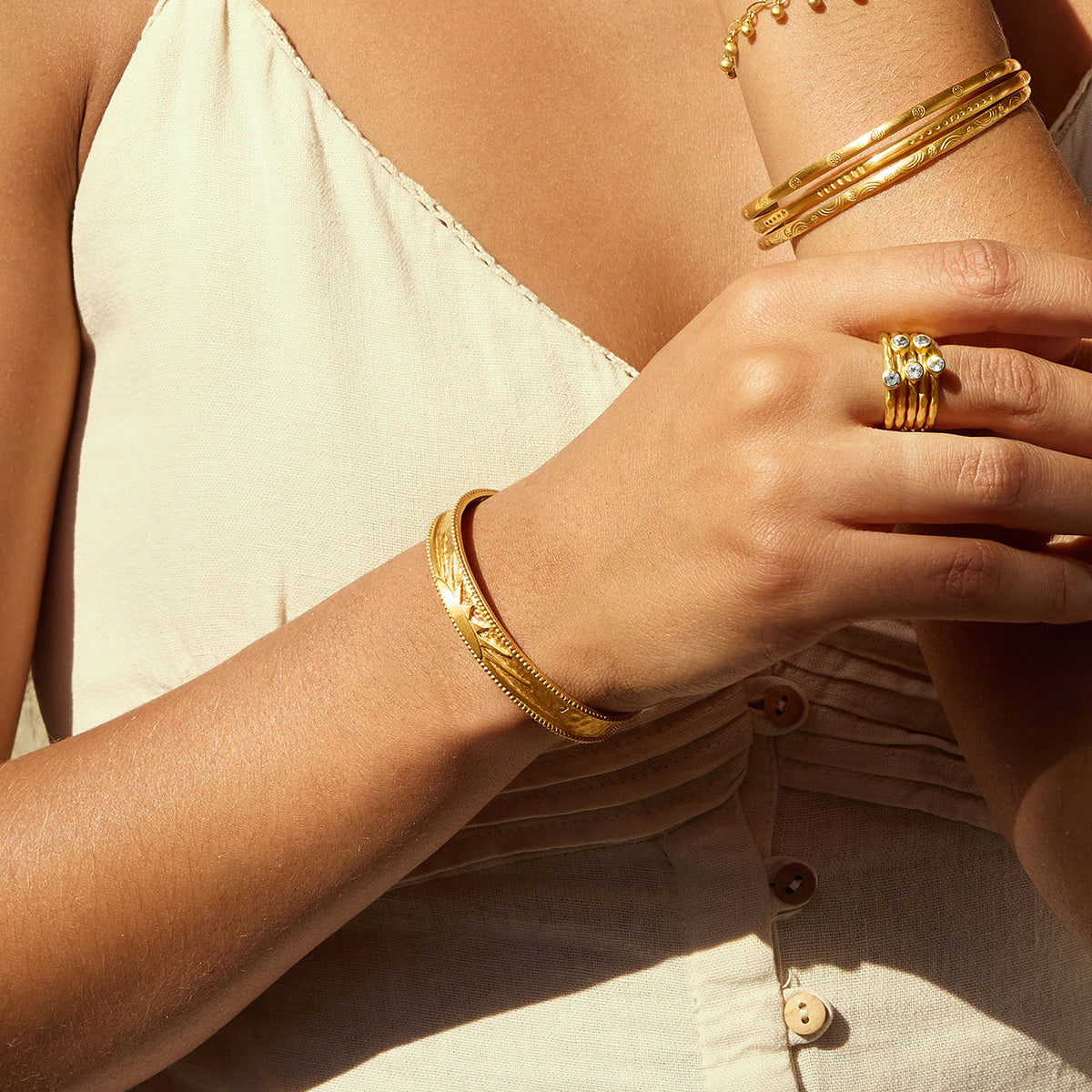 A person elegantly wearing the Breaking Dawn Sunrise Cuff bracelet along with multiple gold bracelets, ideal for those seeking spiritual jewelry. This chic combination symbolizes vitality and positivity, serving as a protective charm for meditation and daily intentions.