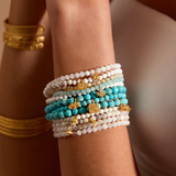 Multiple bracelets including the In Transformation Turquoise Gemstone Bracelet, displaying a blend of materials in a meaningful arm stack. Perfect for spiritual practice, this jewelry supports meditation and personal growth, serving as a talisman and charm for manifestation.
