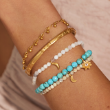 In Transformation Turquoise Gemstone Bracelet worn among other spiritual jewelry pieces. This arm stack showcases the bracelet's vibrant turquoise stones, symbolizing new beginnings and charm, ideal for meditation, yoga, and personal significance.