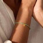 Close-up of the Emerald Lotus May Birthstone Bracelet worn on a wrist, displaying its stunning emerald stones and gold details, ideal for enhancing your spiritual journey, meditation, and connection to the zodiac while serving as a meaningful talisman of abundance and transformation.