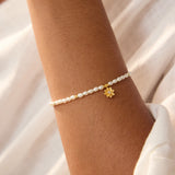 A close-up image of the Pearl Lotus June Birthstone Bracelet featuring a delicate strand of freshwater pearls and an 18kt gold plated lotus flower charm. This spiritual jewelry piece embodies purity and love, making it a meaningful talisman for meditation and manifestation, perfect for those seeking harmony in their zodiac journey. Ideal for yoga enthusiasts and anyone interested in spiritual well-being.