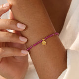 Ruby Lotus July Birthstone Bracelet worn elegantly on a wrist, showcasing its vibrant ruby beads and gold lotus pendant. This spiritual jewelry piece embodies meaning and serves as a talisman for mindfulness, protection, and zodiac energy in daily life.
