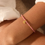 A close-up image of the Pink Tourmaline Lotus October Birthstone Bracelet, featuring a delicate lotus flower pendant in 18kt gold, surrounded by pink tourmaline beads. This spiritual jewelry represents meditation and serves as a talisman for those seeking spiritual alignment, meaning and manifestation in their lives. A beautiful accessory for yoga practitioners and zodiac enthusiasts, celebrating the sun and moon's energy while enhancing personal protection and creativity.