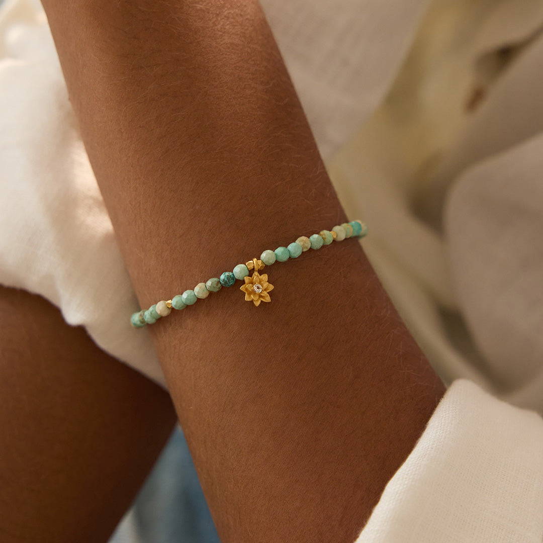 Close-up of the Turquoise Lotus December Birthstone Bracelet worn elegantly, featuring turquoise beads and a gold lotus flower pendant, emphasizing handmade spiritual jewelry. Ideal for meditation and meaningful practices, this bracelet serves as a talisman for protection, healing, and manifestation in yoga and daily life.