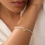 Close-up of a model wearing the White Topaz Lotus April Birthstone Bracelet, showcasing its delicate beauty, spiritual significance, and how it complements a meditative lifestyle and zodiac practices, emphasizing the bracelet's role as a meaningful talisman of manifestation.