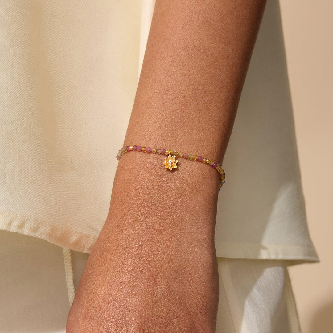 A close-up of the Bloom On Your Path Pink Tourmaline Lotus Bracelet, featuring a delicate gold lotus pendant, symbolizing transformation and renewal. This spiritual jewelry is perfect for meditation and carries the energetic properties of pink tourmaline, making it a beautiful talisman for protection and manifestation. Ideal for yoga practitioners and those who seek meaningful accessories for their zodiac journey.