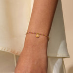 A close-up of the Bloom On Your Path Pink Tourmaline Lotus Bracelet, featuring a delicate gold lotus pendant, symbolizing transformation and renewal. This spiritual jewelry is perfect for meditation and carries the energetic properties of pink tourmaline, making it a beautiful talisman for protection and manifestation. Ideal for yoga practitioners and those who seek meaningful accessories for their zodiac journey.