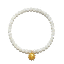 Stretch bracelet with white mother of pearl beads and gold-tone sun charm pendant.