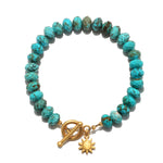 Turquoise beaded bracelet with gold toggle clasp and sun charm pendant.