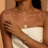 Turquoise beaded bracelet with gold-tone toggle clasp and star charm on model's wrist.