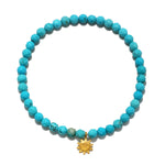 Turquoise beaded stretch bracelet with faceted round stones and a small gold-tone sun charm pendant.