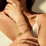 A model wearing the Gold Melody Bracelet Bangle as part of a layered bracelet look, highlighting its symbolic nature in spiritual jewelry and manifestation.