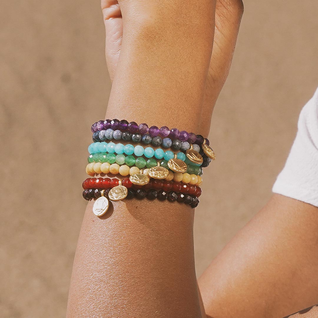 A collection of colorful bracelets including the Sacral Chakra Carnelian Stretch Bracelet, showcasing vibrant stones perfect for meaningful spiritual jewelry, ideal for meditation, yoga, and as a protective amulet.