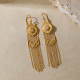 Pair of gold-toned drop earrings with sun motif tops and long chain fringe, displayed on neutral surface.