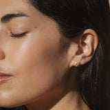 Close-up of a model wearing Light Seeker White Topaz Starburst Stud Earrings, highlighting the golden starburst pattern and white topaz stone. This spiritual jewelry piece serves as a talisman for yoga practitioners, amplifying the powers of manifestation and spirituality while embodying the essence of sun and moon energy.