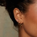 Close-up view of Lotus Petal 14kt Gold Huggie Earrings worn, highlighting their beauty and shine. This piece of spiritual jewelry combines elegance with meaning, serving as a talisman for protection and manifestation in your daily yoga practice.