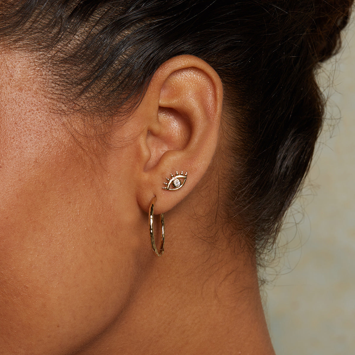 Model wearing Evil Eye Diamond 14kt Gold Stud Earrings, reflecting elegance and spiritual significance. These earrings as a spiritual charm are perfect for anyone practicing meditation and yoga, embodying the protection and blessings of the universe while enhancing your personal style.