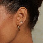 Model wearing Evil Eye Diamond 14kt Gold Stud Earrings, reflecting elegance and spiritual significance. These earrings as a spiritual charm are perfect for anyone practicing meditation and yoga, embodying the protection and blessings of the universe while enhancing your personal style.