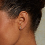 Close-up of a person wearing Moon Diamond 14kt Gold Stud Earrings, showcasing the delicate crescent moon adorned with diamonds. These spiritual earrings serve as a beautiful charm for protection and meaning, ideal for those seeking connection through yoga and meditation.