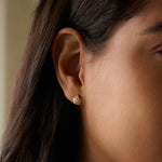A close-up view of Majestic Nature Rainbow Moonstone Earrings worn on an ear, showcasing the teardrop-shaped rainbow moonstone cradled in golden light. These earrings symbolize hope and protection, making them perfect for spiritual jewelry seekers, meditation practitioners, and those who appreciate meaningful talismans for manifestation and zodiac alignment in yoga.