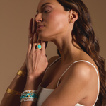 An elegant model adorned with Soul Renewal Gold Lotus Earrings, alongside a stunning ring, emphasizing the beauty of spiritual jewelry that resonates with astrology and the meanings of meditation, manifestation, and protection.