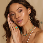 Elegant portrayal of a model adorned with the Transformed by Light Lotus Linear Earrings and other spiritual jewelry pieces. These earrings symbolize meaningful connections to life's potential and charm, perfect for those interested in zodiac, malas, and meditation.