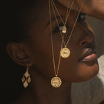 A model elegantly displays the Adorned with Light Chandelier Earrings alongside layered necklaces, capturing a moment that resonates with the essence of spiritual jewelry. Ideal for yoga practice or meditation, this earring design combines beauty and meaning, reflecting the sun and moon in its aesthetic.