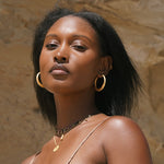 A model wearing Timeless Beauty Dot Hoop Earrings, showcasing the beautiful gold hoops paired with layered necklaces, radiating elegance and spirituality, perfect for yoga enthusiasts who appreciate the meaningful connections of sun and moon energies.