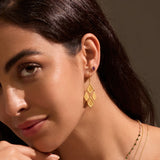 A close-up of a model wearing All Love Garnet Stud Earrings paired with intricate gold earrings, emphasizing the earrings' roles as talismans for love and meaning in spiritual life and yoga.