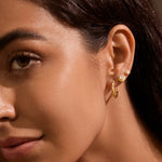 A close-up of a woman wearing the Kindred Spirits Sparkling Moon Hoops, showcasing the 18kt gold plated crescent moon design adorned with sparkling white topaz. This spiritual jewelry is perfect for yoga enthusiasts and those seeking meaningful talismans for protection and manifestation, embodying the essence of the sun and moon in their radiant beauty.