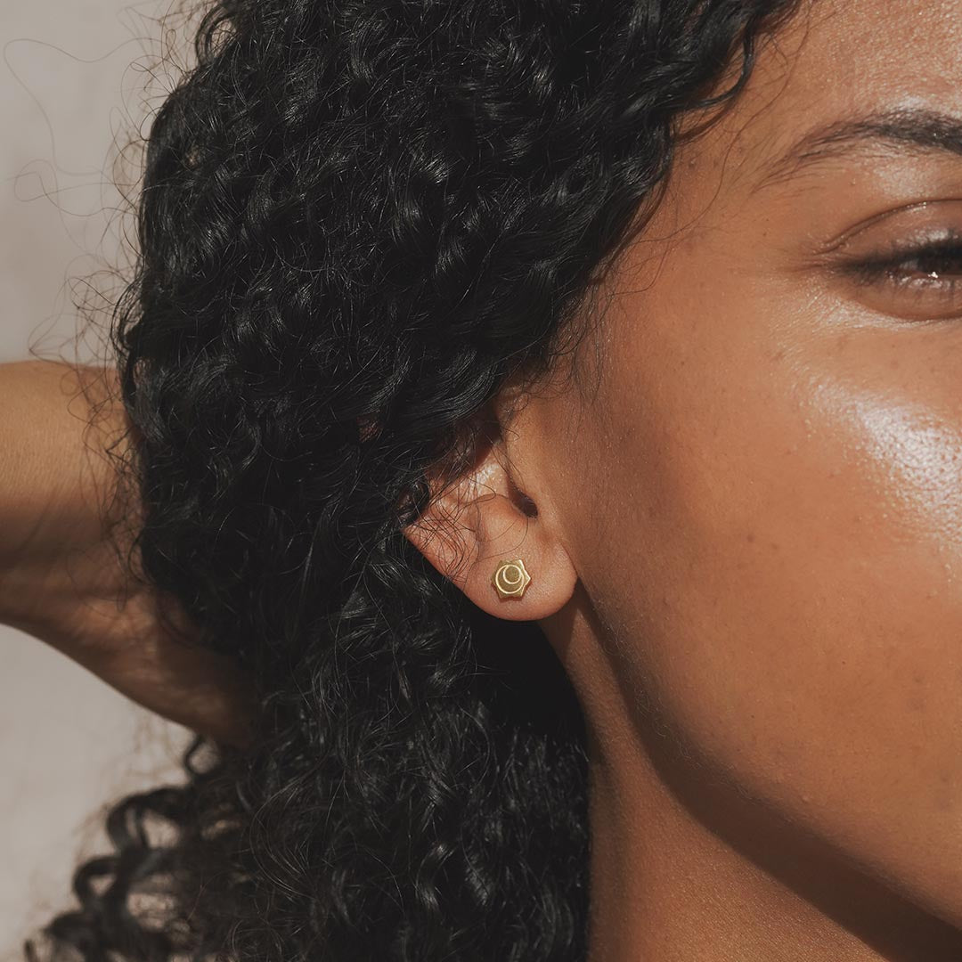 A model wearing Sacral Chakra Stud Earrings that beautifully highlight the ear. These earrings are a stylish choice for spiritual jewelry, representing protection and meaning, perfect for yoga practices and meditation, symbolizing the sun and moon energy connected to creativity and desires.
