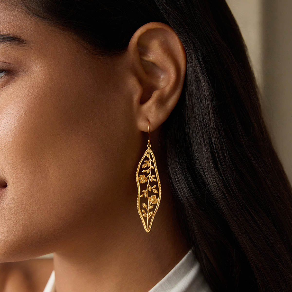 Close-up of a model wearing the Expanding Beauty Lotus Earrings, showcasing the intricate gold-plated design. These earrings represent spiritual meaning and transformation, ideal for yoga enthusiasts seeking a talisman for manifestation and protection.