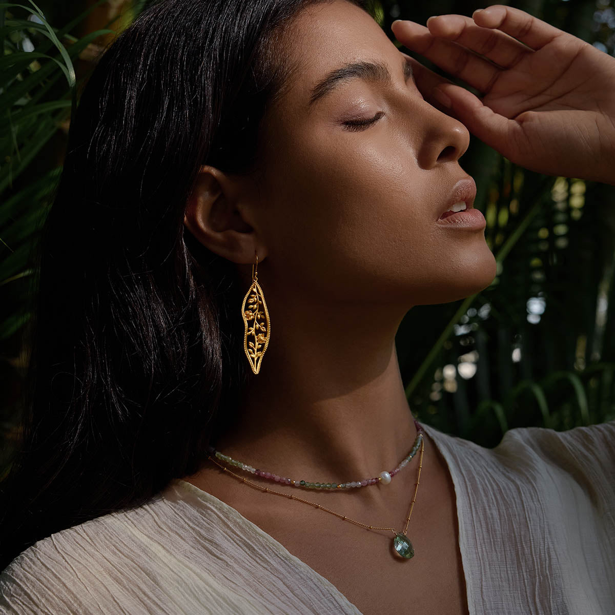 A model in a natural setting wearing the Expanding Beauty Lotus Earrings along with layered necklaces, highlighting the earrings’ elegant design. These pieces of spiritual jewelry embody the essence of transformation, making them perfect for meditation and yoga practices.