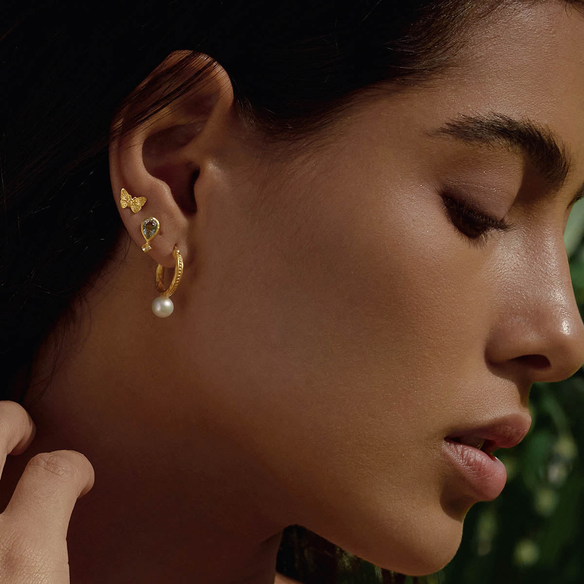 Side profile of a model wearing Nature's Harmony Pearl Hoop Earrings alongside various styled earrings. Each piece serves as spiritual jewelry, radiating significance in protection, talismans, and the pursuit of a meaningful life through yoga and meditation.