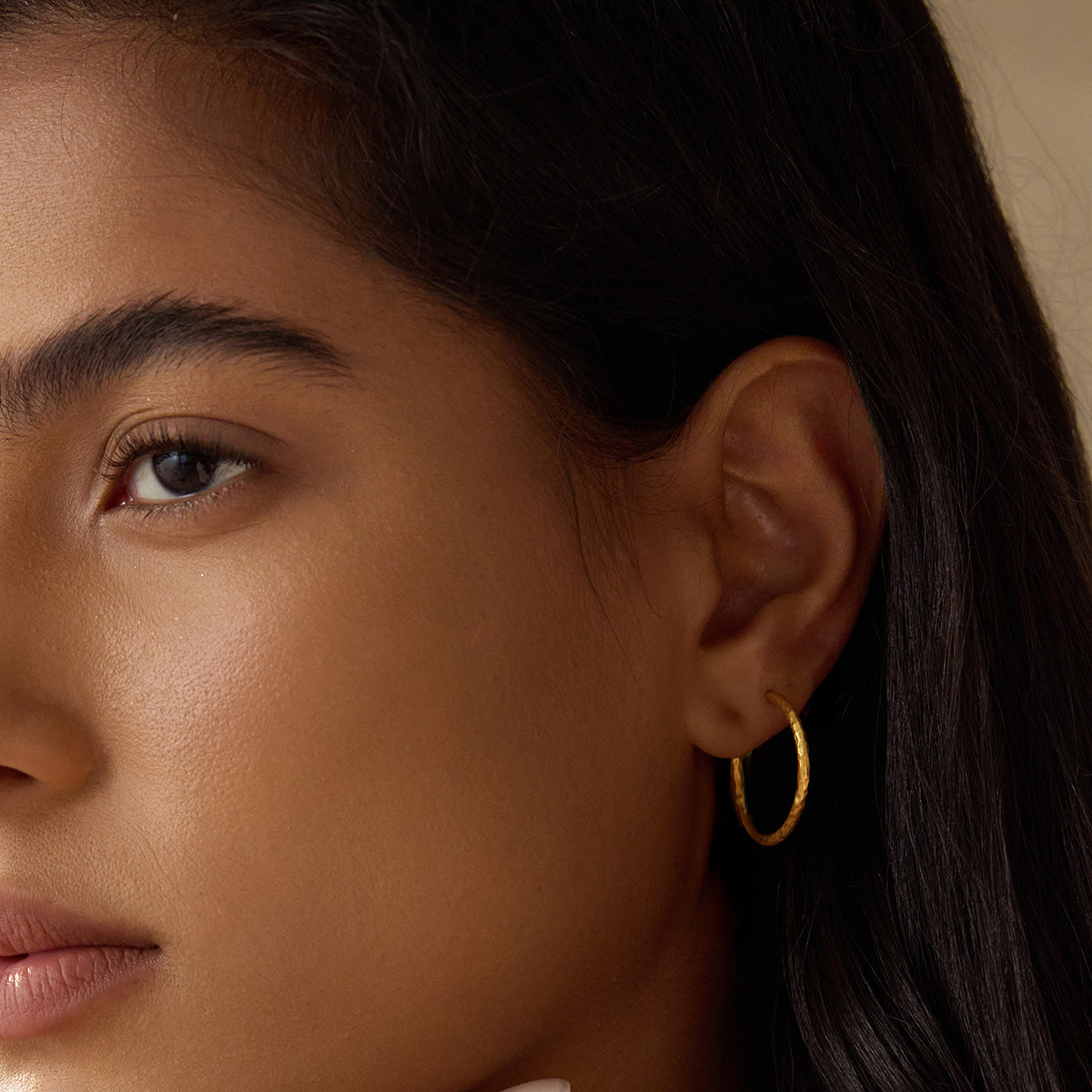 Close-up of a model wearing Textured Gold Medium Hoop Earrings, highlighting their elegant look and minimalist appeal. These hoops are part of a spiritual jewelry collection, perfect for yoga enthusiasts and those seeking talismans that embody meaning and connection to the sun and moon.