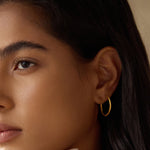 Close-up of a model wearing Textured Gold Medium Hoop Earrings, highlighting their elegant look and minimalist appeal. These hoops are part of a spiritual jewelry collection, perfect for yoga enthusiasts and those seeking talismans that embody meaning and connection to the sun and moon.