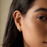 Close-up of Textured Gold Mini Hoop Earrings worn on an ear, illustrating their minimalist impact as spiritual jewelry ideal for enhancing your style during yoga or meditation sessions, connected with meaningful symbolism.