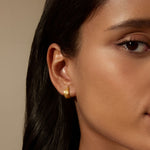 Model wearing Little Joys Dot Huggie Hoop Earrings in a serene pose. The 18kt gold plated earrings add a meaningful touch to spiritual practices like yoga and meditation, embodying protection and the essence of the sun and moon.
