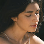 The Scattered Stardust Celestial Moon and Star Pavé Hoop Earrings worn by a woman, enhancing her elegant look. This spiritual jewelry symbolizes the deep connection to the cosmos, ideal for those practicing yoga and meditation while seeking meaningful energies of the zodiac, sun, and moon.