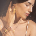A woman showcasing the Cascade of Starlight Moonstone Fringe Drop Earrings, embodying spiritual jewelry and meditation. The delicate golden chains shimmer, representing a talisman for protection and meaning, perfect for manifestation in yoga practice.