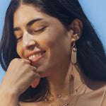 A joyful woman smiling while adorned with the Cascade of Starlight Moonstone Fringe Drop Earrings, embracing the essence of spiritual jewelry. These earrings serve as a talisman for hope and manifestation, ideal for yoga and meditation.